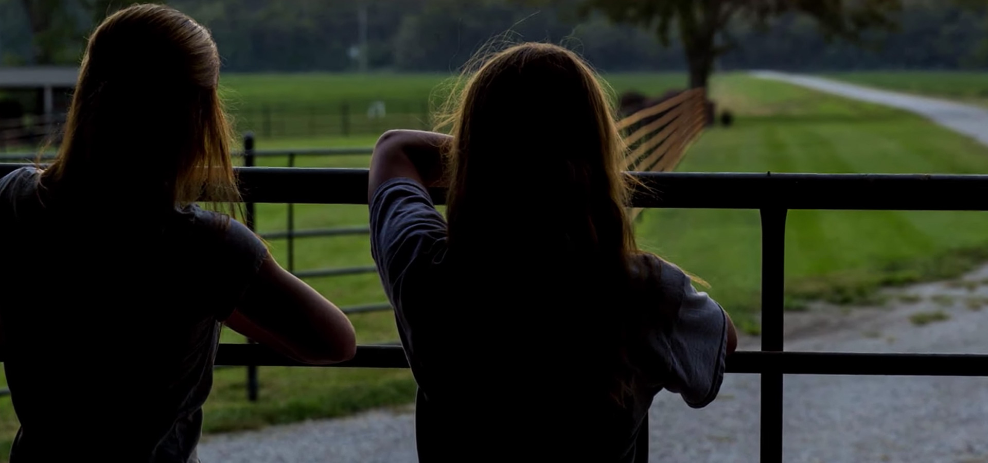 two women looking past a fence